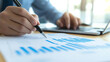 © Tahsin - Business professional analyzing financial graphs and trends with a laptop at the office