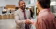 © CineLens/peopleimages.com - Handshake, hotel lobby and business people with greeting, welcome and meeting for conference or seminar. Man, woman and hello for b2b, partnership and work trip for hospitality and collaboration