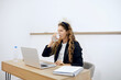 © boomeart - Businesswoman taking a break to drink water while working at a desk in a modern office