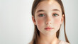 © THINGDSGN - A young girl with green eyes and long brown hair poses thoughtfully against a soft, neutral background in natural light, kid model with copy space