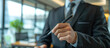 © FNB business illust - close up hand businessman stand in black suit pointing a pen at front camera and copy space blur office background