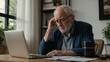 © zxappii - Senior Man Concentrating on Laptop: An elderly man with a serious expression sits at his desk, deep in thought as he works on his laptop. He is wearing glasses and a blue sweater.