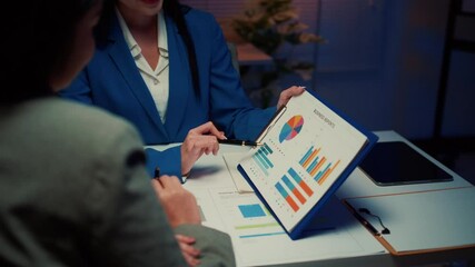 Poster - Businesswoman in a blue blazer points at charts on a clipboard while explaining a strategy to her business partner at the office
