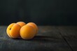 © nikolettamuhari - apricots on a dark wooden table, shot from a low angle with soft lighting....
