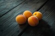 © nikolettamuhari - apricots on a dark wooden table, shot from a low angle with soft lighting....