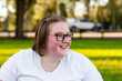 © Austockphoto - Smiling young woman in glasses side on portrait relaxing on the grass in parkland