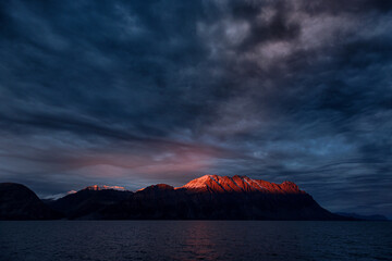Wall Mural - setting sun glows red over the mountains of antarctic sound, king christian x land, northeast greenl