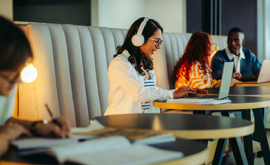 Joyful students coworking in a vibrant shared workspace featuring collaboration and productivity with laptops and headphones