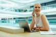 © Jacob Lund - Smiling blonde salesperson using a phone in modern office
