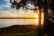 © Austockphoto - Sunset over lake with silhouetted trees beside peaceful water