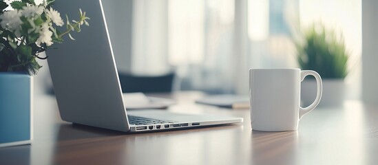 Fototapete - Home office desk with a laptop coffee mug and notebook surrounded by natural light and plants emphasizing a calm and productive atmosphere Teleworking concept with side empty space for text