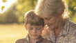 © wernerimages - An elderly woman shares a peaceful and intimate moment with a young boy, basking in soft, warm sunlight, capturing a tender familial bond in nature.