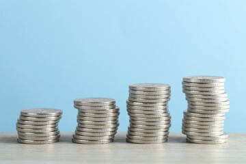 Poster - Stacked coins on wooden table against light blue background, closeup. Salary concept