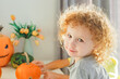 © Olga Gimaeva - Three real siblings standing together against white wall at cozy home and holding in their hands three orange and green pumpkins with scary faces, happy halloween at home