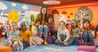 © Gorodenkoff - Portrait of Happy Diverse Children Posing Together with a Female Preschool Teacher in a Modern Kindergarten. Educator and Beautiful Small Kids Looking at Camera, Smiling, Waving Hands