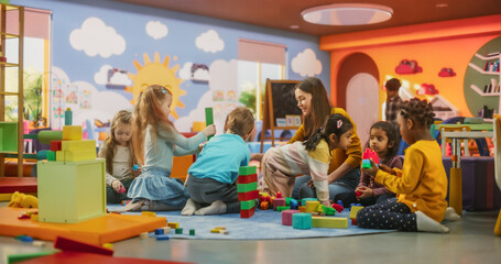 Wall Mural - Cheerful Diverse Kids Playing with Colorful Building Block Toys in Kindergarten. Group of Multiethnic Boys and Girls Playing Together with a Female Teacher in a Modern Daycare Center