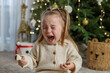 © Olha Tsiplyar - Kid crying while sitting near christmas tree in cozy living room during holiday season