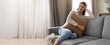 © Prostock-studio - Bright afternoon light fills a cozy living room where a young woman sits on a couch. She smiles while holding a soft pillow, enjoying a moment of relaxation in her stylish space.