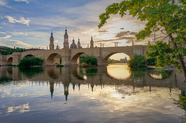 Wall Mural - View on the Stone Bridge and Basilica of Our Lady of the Pillar on the banks of Ebro river at sunset. Zaragoza, Spain