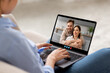© Prostock-studio - A woman sits comfortably on a couch, connecting with a friendly couple through a video call on her laptop, showcasing a warm and engaging conversation in a cozy setting.