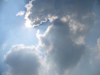 natural blue and white sky background with sun rays coming out from behind clouds. topics: weather, 