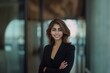 © Poly_Picture AI_Art - Portrait of a beautiful, smiling business woman in a modern office, wearing a black suit and blazer with a blurred background-  Generative AI