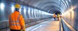 © Jiraporn - Construction workers in safety gear working inside a lit tunnel.