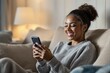 © Derek Brumby - Smiling Young Woman Engaged in Mobile Phone Activity in Cozy Living Room