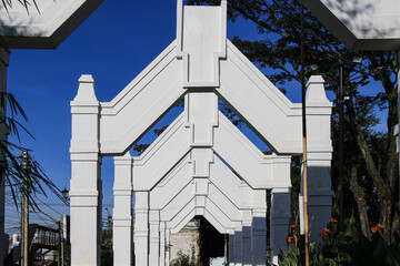 Poster - A white architectural archway with mesmerizing geometric patterns. The structure creates a sense of grandeur and symmetry against bright blue sky.