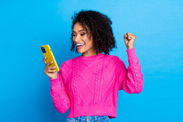 Poster - Photo of nice young girl use phone raise fist wear pink sweater isolated on blue color background