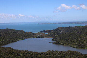 sweeping view of a reservoir, dam and river beyond draining into a deep blue ocean bay