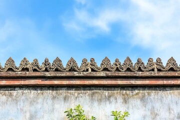 Wall Mural - Ornate stone wall with intricate carvings against a blue sky.