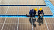 © ultramansk - Photovoltaic engineers work on roof top warehouse. workers Inspect and repair the solar panel equipment roof structural. Engineer working set up electrical renewable energy for sustainability.