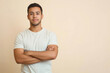 © KumCup - young man with crossed arms stands confidently against neutral background, exuding calm and approachable demeanor