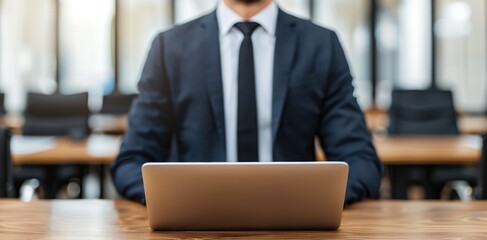 Poster - A professional man in a suit sits at a desk with a laptop, embodying focus and readiness for work in a modern office environment.
