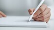 © nattapon98 - A close-up of a hand holding a pen, poised above a blank sheet of paper, ready to write or draw.