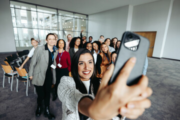 Wall Mural - Corporate facilitator taking selfie with diverse team during a professional event