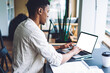 © BullRun - Dark skinned male freelancer working remotely on modern laptop computer with blank screen for internet web advertising, millennial student preparing to exam with web information from netbook