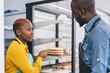 © BullRun - Black seller in uniform speaking to colleague about cake
