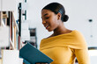 © BullRun - Smiling black female reading book near bookcase