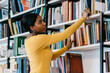 © BullRun - Black student taking book from bookshelf