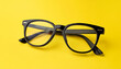 © hardvicore - Pair of black eyeglasses against yellow backdrop. For promo poster or banner.