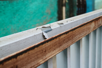 Poster - A close-up view of a rusted metal railing. The metal is worn and weathered, showing signs of age and neglect. Close-up of Rusty Metal Railing with peeling paint stands against a turquoise wall