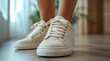 © Aziz - Closeup of white leather sneakers worn by a woman.