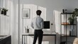 © 69 - Monochrome home office with a man standing, surrounded by simple decor and minimalistic furniture. Clean, modern aesthetic.