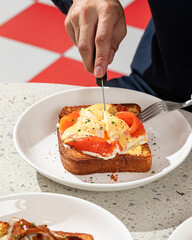 Wall Mural - Man eating brioche breakfast toast with egg and salmon