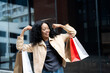 © Bavorndej - Cheerful woman showing off her shopping bags in an urban setting, celebrating a successful shopping day with enthusiasm.