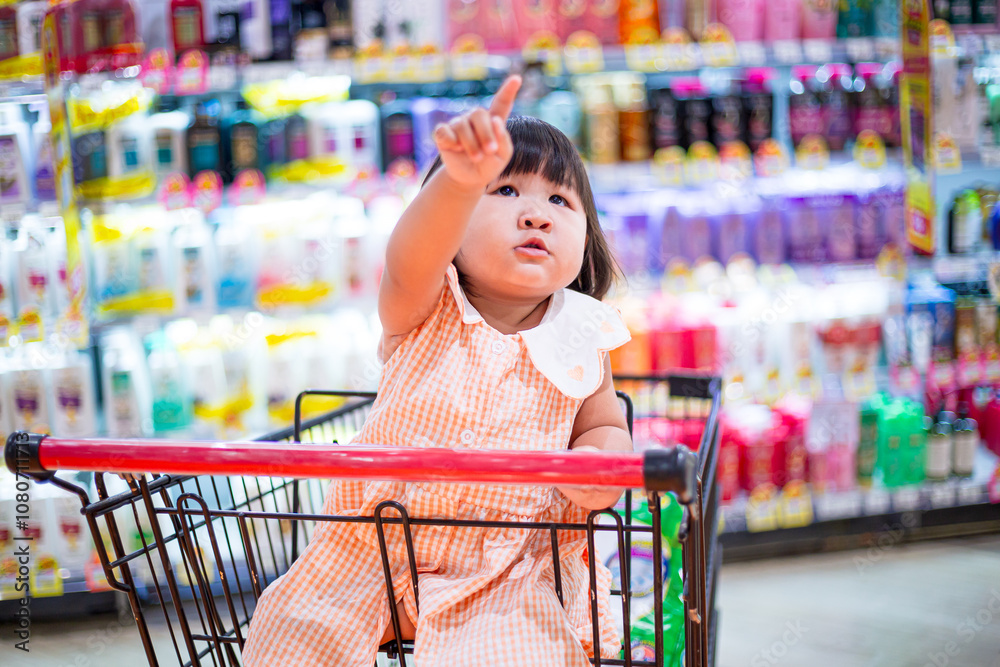 Cute girl sitting on a shopping cart in a shopping mall,Happy little ...