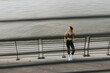 © BGStock72 - A confident athlete enjoys a moment of reflection while stretching on a riverfront path during golden hour