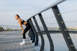 © BGStock72 - A young woman takes a moment to catch her breath after an intense run along a scenic riverside path during a sunny afternoon